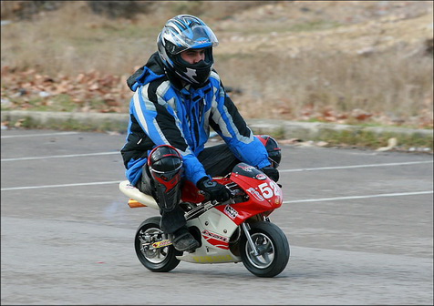 Человек в шлеме едет на маленьком мотоцикле